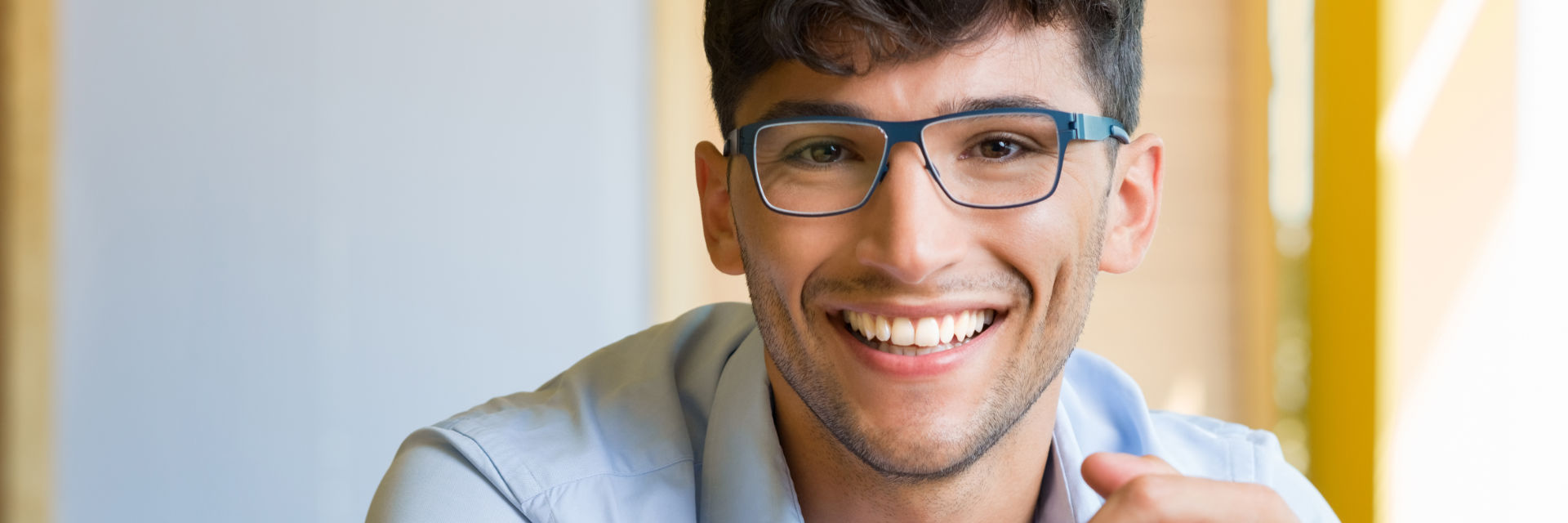 A happy young businessman wearing glasses showing his nice teeth in a smile.