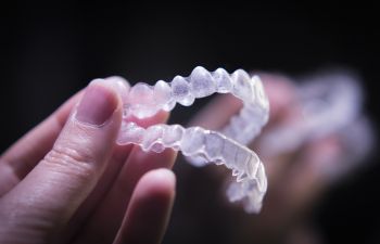 Person holding a set of clear dental aligners.